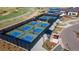 Aerial view of several fenced pickleball courts with blue playing surfaces near a pond and community buildings at 21701 E 50Th Dr, Aurora, CO 80019