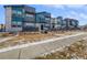 Modern townhouses with gray and teal exterior, private fenced yards, and a sidewalk at 4758 Kittredge St # 2, Denver, CO 80239