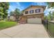Two-story home featuring a spacious driveway, a charming brick exterior, and manicured lawn at 11936 E Oregon Cir, Aurora, CO 80012