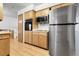 Modern kitchen with stainless steel appliances, wood cabinetry, and hardwood floors at 11936 E Oregon Cir, Aurora, CO 80012