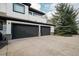 Spacious three-car garage featuring black doors and a large concrete driveway at 10667 E Goose Haven Dr, Lafayette, CO 80026