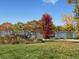 Scenic lake view with colorful fall trees lining the shore in a lush green lawn at 10667 E Goose Haven Dr, Lafayette, CO 80026