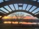 Breathtaking sunset view over a calm lake from a covered outdoor space, featuring a beautiful color sky at 10667 E Goose Haven Dr, Lafayette, CO 80026