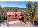 Aerial view of the home with a red roof surrounded by lush greenery at 4520 Forest Hill Rd, Evergreen, CO 80439