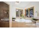 Bright bathroom features a soaking tub with views, tiled shower, and skylight at 4520 Forest Hill Rd, Evergreen, CO 80439