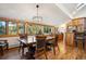 Warm and inviting dining area featuring wood floors, modern chandelier, and large windows with green views at 4520 Forest Hill Rd, Evergreen, CO 80439