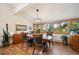 Well-lit dining room with chandelier, wood floors, and large windows offering picturesque outdoor views at 4520 Forest Hill Rd, Evergreen, CO 80439