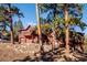 View of the home's exterior with wooden facade, balcony, and front porch with natural landscaping at 4520 Forest Hill Rd, Evergreen, CO 80439