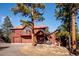 Charming home with a red roof and wood siding nestled among mature trees at 4520 Forest Hill Rd, Evergreen, CO 80439