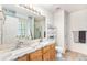 Bright bathroom with double vanity, granite countertop, framed mirror, and tiled floors at 9650 Raven St, Firestone, CO 80504