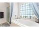Bathroom featuring a bathtub, glass shower, checkered curtain, and soft lighting at 9650 Raven St, Firestone, CO 80504