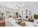 Bright living room with neutral decor, ceiling fan, large windows, and sliding glass door to covered patio at 9650 Raven St, Firestone, CO 80504