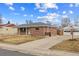 A cozy brick home with a long driveway and a detached garage, set against a blue sky at 6270 Harlan St, Arvada, CO 80003