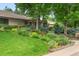 Beautifully landscaped front yard with lush green grass, colorful flowers, bushes, and mature trees at 3401 E Kentucky Ave, Denver, CO 80209
