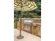 Stone outdoor kitchen featuring a stainless steel grill, tiled backsplash, and umbrella for shade at 3401 E Kentucky Ave, Denver, CO 80209