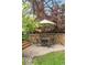 Patio dining set with stone surround is nestled in a yard with mature shade trees at 3401 E Kentucky Ave, Denver, CO 80209