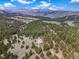 Panoramic view of a large stone home nestled in a lush, green valley with mountain backdrop at 77 Krestview Ln, Golden, CO 80401