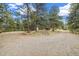 Gravel driveway splitting at a fork, surrounded by mature trees and landscaping at 77 Krestview Ln, Golden, CO 80401