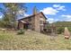 A charming stone home with a balcony and chimney set amidst a grassy landscape at 77 Krestview Ln, Golden, CO 80401