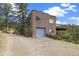 Exterior of home with gray garage door, stone facade, and treed landscape at 77 Krestview Ln, Golden, CO 80401