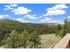 This exterior view from a deck shows vast tree coverage and blue sky with puffy clouds at 77 Krestview Ln, Golden, CO 80401