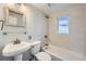 Updated bathroom with a pedestal sink, tiled walls, and a tub-shower combo at 3348 S Corona St, Englewood, CO 80113