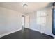 Minimalist bedroom featuring dark floors, simple light fixture, and a glimpse into an adjacent room at 3348 S Corona St, Englewood, CO 80113