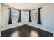 Light filled bedroom with dark wood floors, two windows with blue curtains, and a modern ceiling light at 3348 S Corona St, Englewood, CO 80113