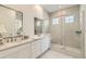 Bright bathroom features double vanity, a large mirror, and glass enclosed shower at 15788 Valentia St, Thornton, CO 80602