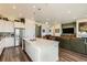Open kitchen with white cabinets, stainless appliances, island with seating, and open to living room at 15788 Valentia St, Thornton, CO 80602