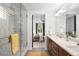Bathroom featuring double sinks, wood cabinets, and a walk-in shower with mosaic tile, creating a spa-like retreat at 1947 King St, Denver, CO 80204