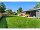 Expansive backyard with a lush lawn, wooden fence, and covered patio with a hot tub and dining area at 5601 E Colorado Ave, Denver, CO 80224