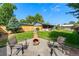 Backyard showcasing a fire pit area with chairs, grassy lawn, and a wooden privacy fence at 5601 E Colorado Ave, Denver, CO 80224