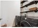 Modern laundry room with dark front load washer and dryer and rustic shelving at 7227 Clarke Dr, Frederick, CO 80530