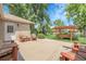 Relaxing backyard concrete patio with striped cushioned seating, a swing, lush grass, and mature landscaping at 1091 E Pinewood Ave, Centennial, CO 80121