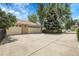 Two-car garage and expansive driveway, bordered by trees and shrubs, offering ample parking and curb appeal at 1091 E Pinewood Ave, Centennial, CO 80121