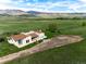 Aerial view of charming home situated in a vast green pasture with a mountain backdrop at 8602 N 39Th St, Longmont, CO 80503
