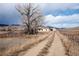 Exterior shot of a house and adjacent barn, with a dirt road leading to the buildings at 8602 N 39Th St, Longmont, CO 80503