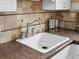 Close-up on a large white kitchen sink with stainless steel fixtures, countertop, and backsplash at 2047 S Milwaukee St # 4, Denver, CO 80210