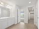 Bright bathroom with double sinks, white cabinets, an adjacent bedroom and walk in closet with vinyl flooring at 8819 Sedalia St, Commerce City, CO 80022