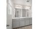 Bright bathroom features a double sink vanity with gray cabinets and a large mirror at 8819 Sedalia St, Commerce City, CO 80022