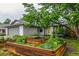 Landscaped front yard featuring raised garden beds and mature trees, creating a serene and inviting curb appeal at 182 Lois Cir, Louisville, CO 80027