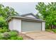 Spacious garage with a modern gray door, complemented by a lush garden, offering convenience and charm at 182 Lois Cir, Louisville, CO 80027