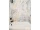 Detail of a modern bathroom tub featuring artistic marble-style tiling and matte black hardware at 2988 S Hannibal St, Aurora, CO 80013