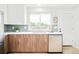 A kitchen features modern wood cabinets, tiled backsplash, a stainless steel dishwasher, and a bright window at 2988 S Hannibal St, Aurora, CO 80013