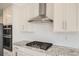 Modern kitchen with white cabinets, granite countertops, and stainless steel range hood at 15243 W 69Th Ave, Arvada, CO 80007