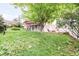 Spacious backyard featuring lush green grass, mature shade trees, and inviting deck area with a fire pit at 6535 Balsam St, Arvada, CO 80004