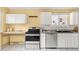 Sunlit kitchen with stainless steel appliances, neutral countertops, and white cabinets at 6535 Balsam St, Arvada, CO 80004