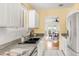 Bright kitchen featuring granite countertops, white cabinets, stainless steel sink and view of the dining room at 6535 Balsam St, Arvada, CO 80004