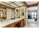 Well-lit bathroom with double sinks, ample counter space, and a view into an adjoining bedroom at 6115 W Mansfield Ave # 242, Denver, CO 80235